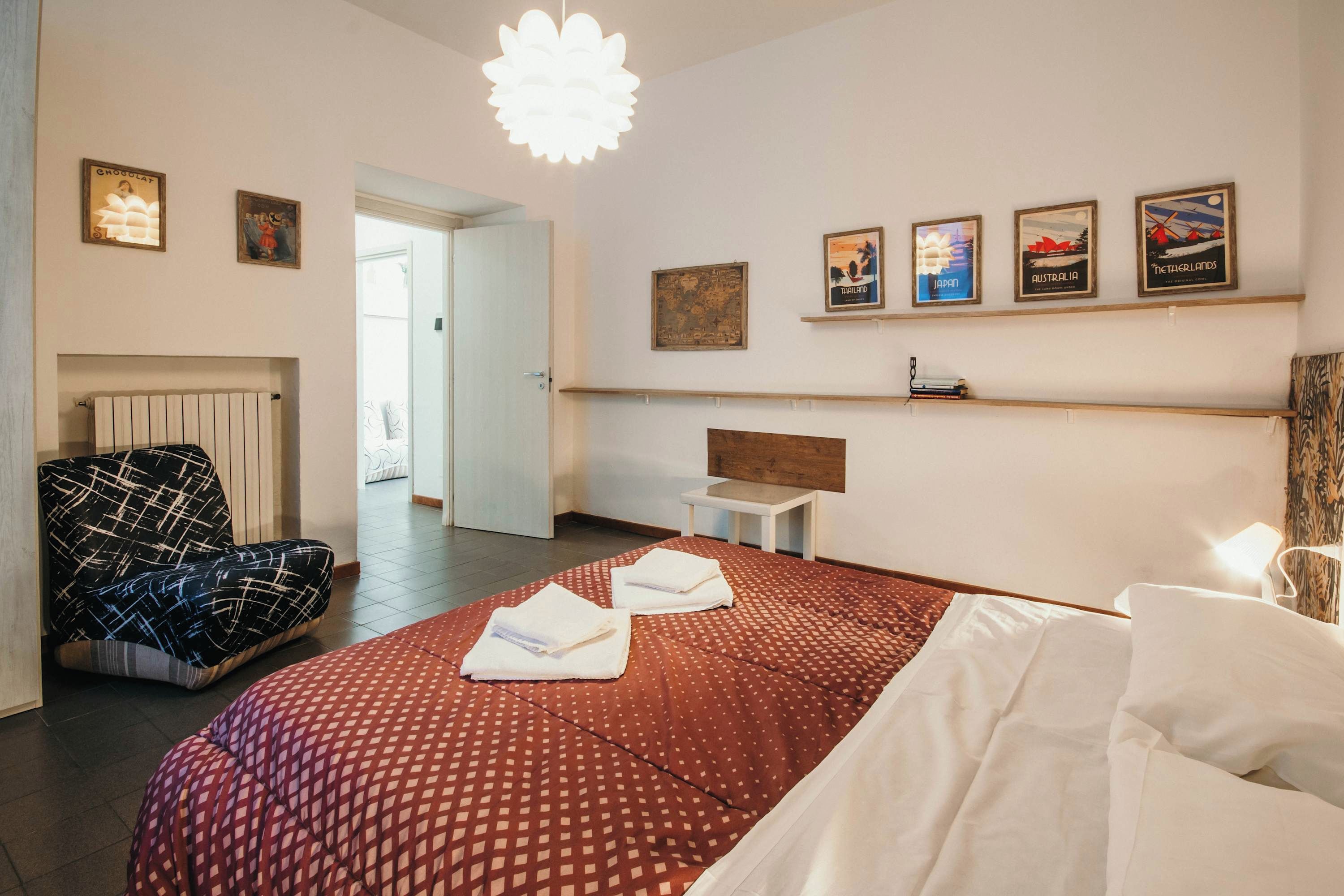 Una habitación de hotel con una cama, una silla, una mesita de noche y decoración en la pared.