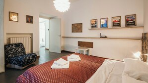 Ein Hotelzimmer mit Bett, Sessel, Nachttisch und Wandbildern.