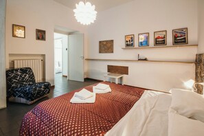 Ein Hotelzimmer mit Bett, Sessel, Nachttisch und Wandbildern.