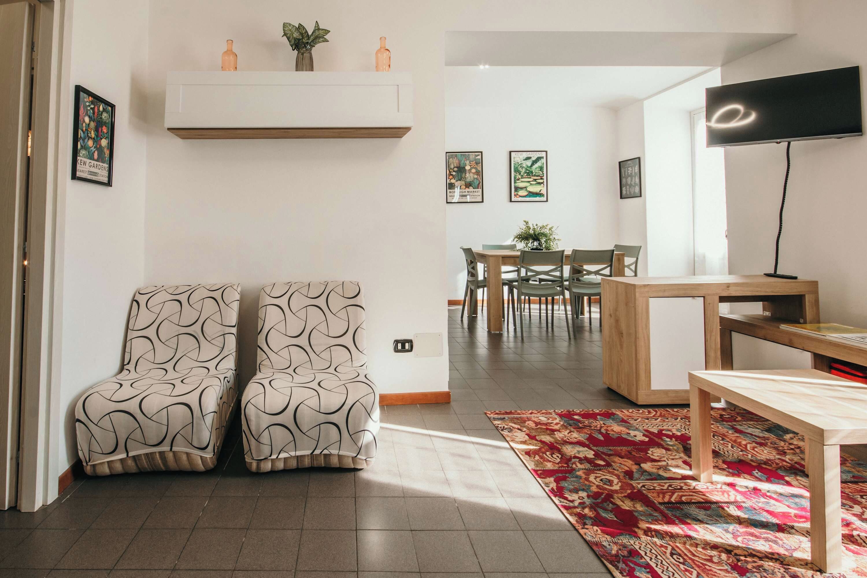 Una sala de estar moderna con un sofá, una mesa de centro, un televisor y un comedor con sillas y una mesa.