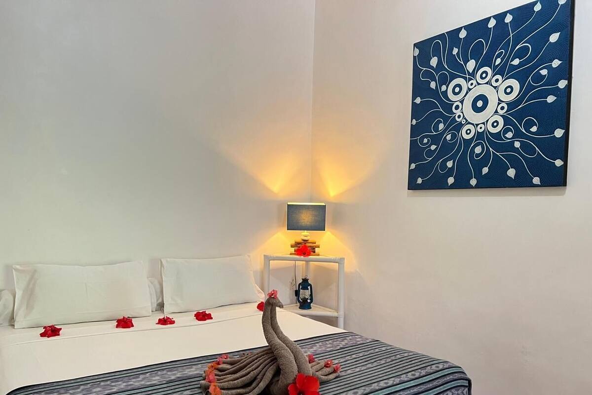 Una habitación de hotel con una cama, una mesita de noche con lámpara y una obra de arte en la pared.