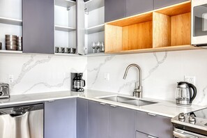 Enjoy a comfortable stay with a fully equipped kitchen featuring a stainless steel sink, coffee maker, and ample storage.