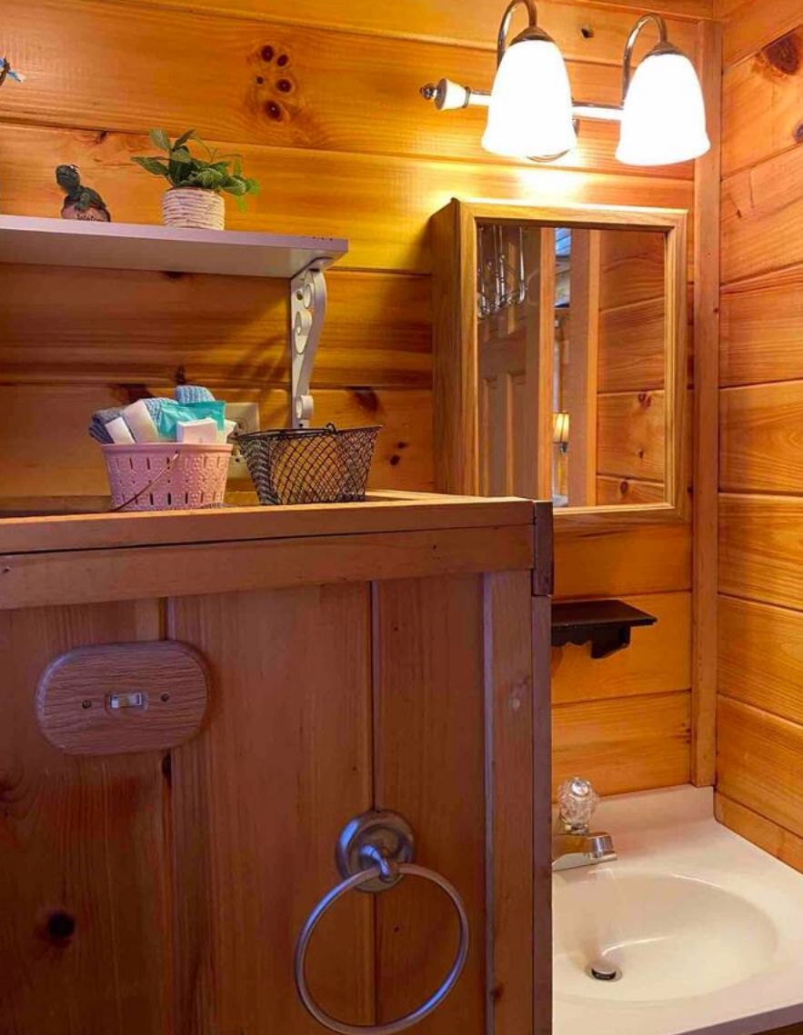 Ein Badezimmer aus Holz mit Waschbecken, Spiegel und zwei Wandleuchten.