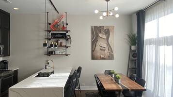 A modern kitchen with a marble island, a dining area with a wooden table and chairs, and a living space with a sofa and a coffee table.