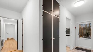 Ein modernes Interieur mit einem Flur, der zu einem Raum mit einem schwarzen Wandschrank und einem Fenster mit Blick auf Bäume führt.