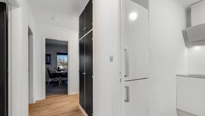Eine moderne Küche mit weißen Schränken, einem schwarzen Kühlschrank und Holzboden.