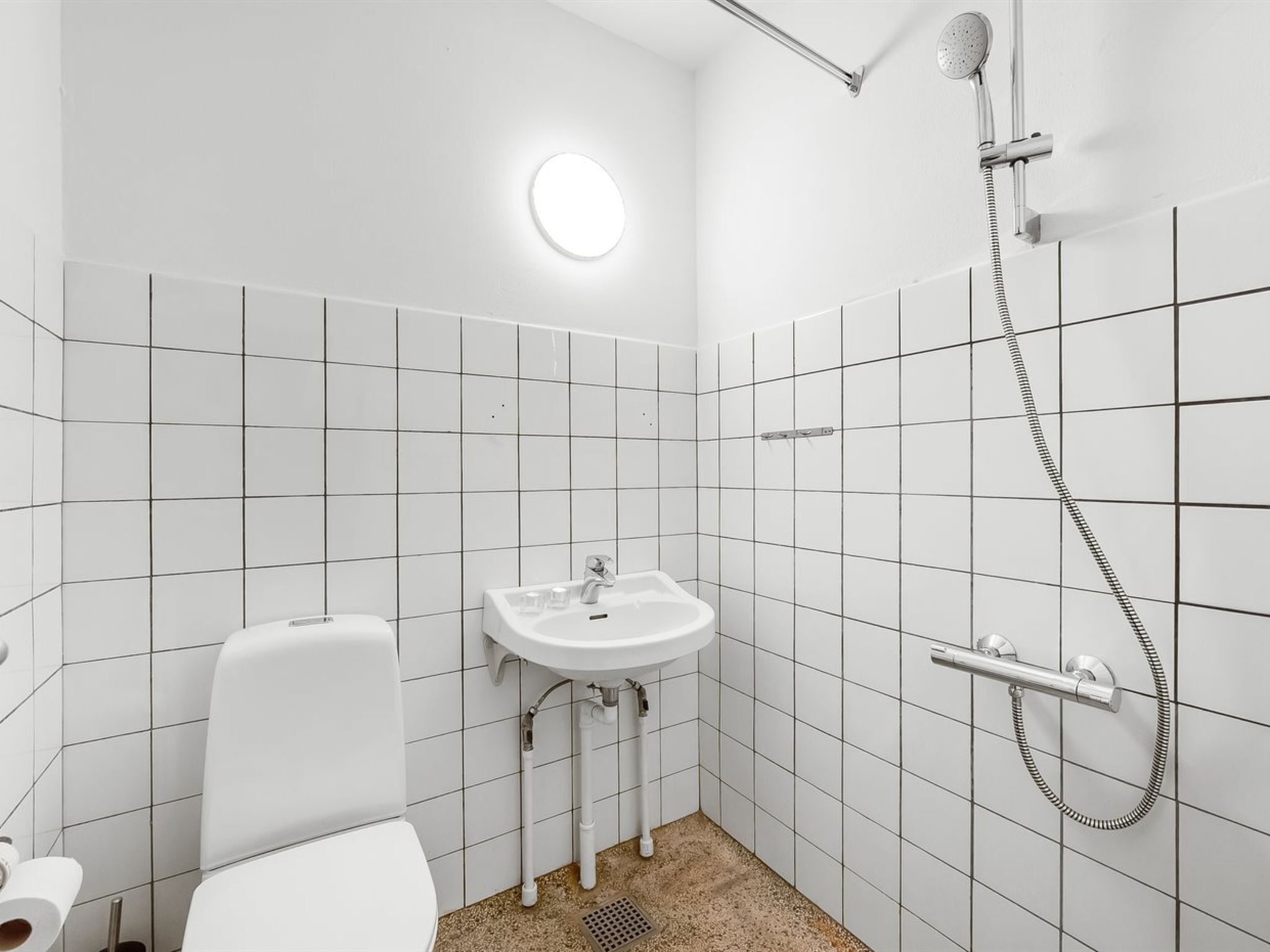Un baño pequeño y blanco con inodoro, lavamanos y ducha.
