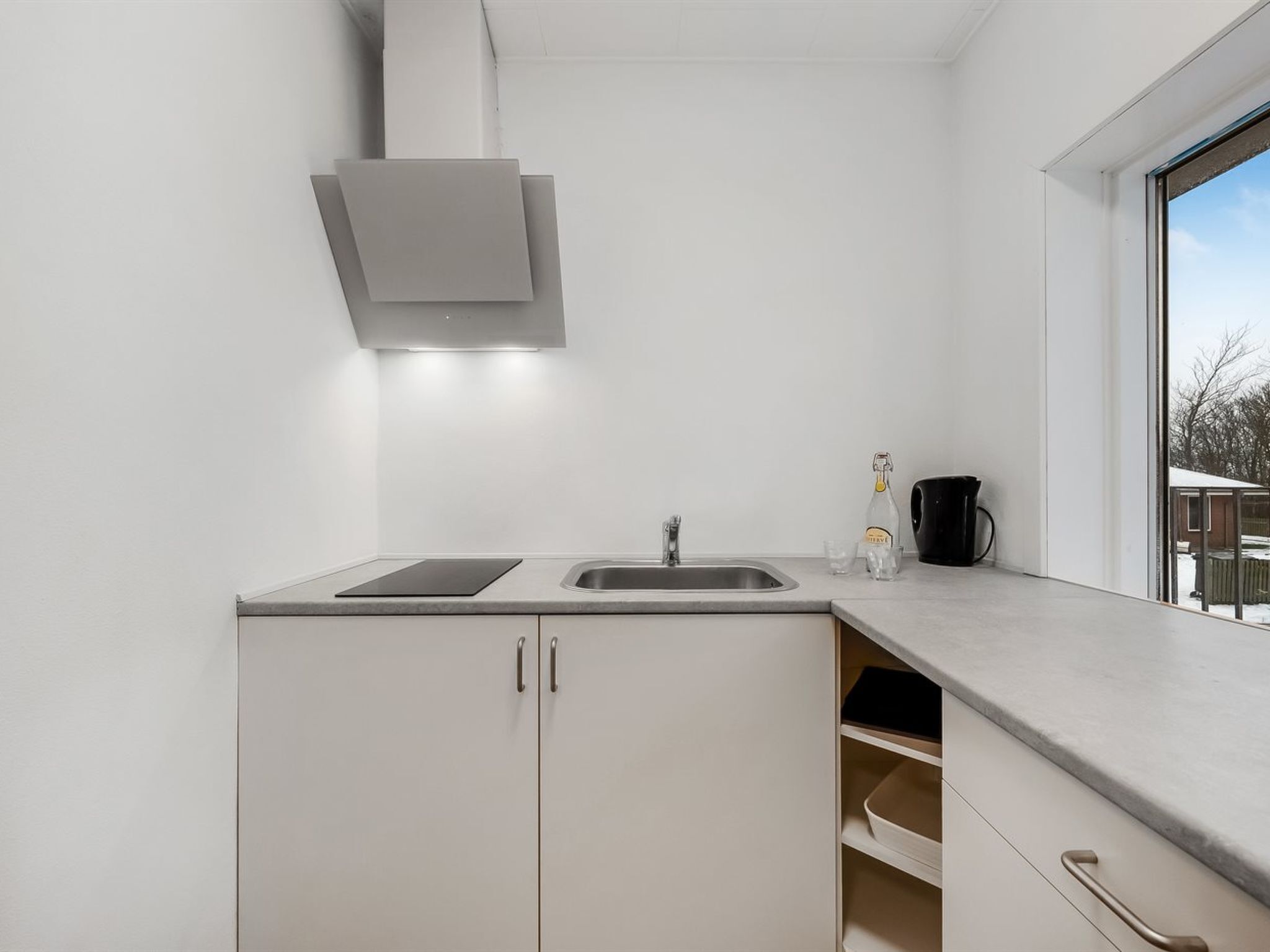 Eine moderne Küche mit eingebautem Herd, einer Spüle und einem Fenster mit Blick ins Freie.