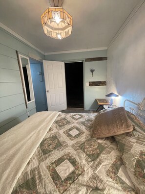 A bedroom with a bed, a nightstand, a lamp, and a door. - Simple luxury in a country setting  (Idaho Falls)
