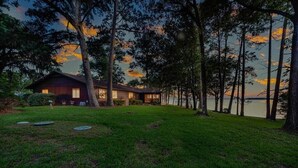 Uma casa com um gramado amplo e vista para a água.