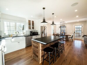Una cocina moderna con armarios blancos, una isla de madera y taburetes negros.