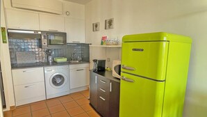 A compact kitchen with a washing machine, microwave, and a bright green refrigerator. - Studio - 2/4 people - Sea view - AC - Residence swimming pool - Wifi - Beach - Sainte Maxime (STE MAXIME)