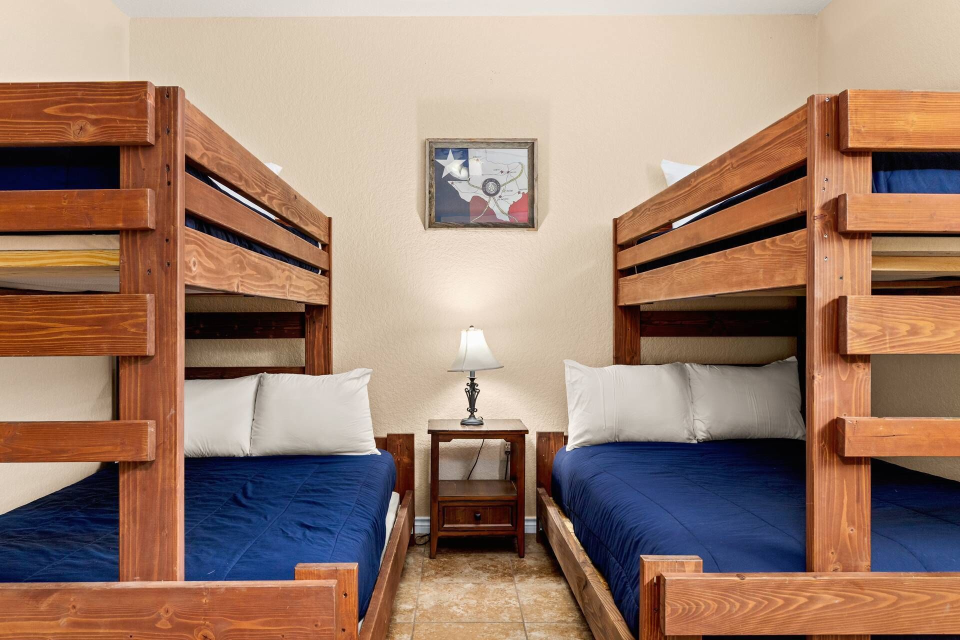 A room with two bunk beds, a small table with a lamp, and a map on the wall.