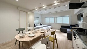 A modern, open-plan living space with a dining area, kitchenette, and a cozy seating area with a sofa and a bed. - F style namiki Studio Apt Great Location for 6Ppl (Hiroshima)