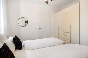 Une chambre avec deux lits, une armoire, un miroir et une porte.