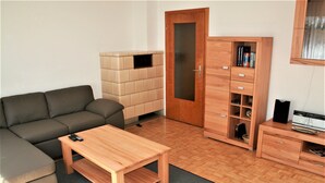 Un salon avec un canapé, une table basse en bois, un meuble contenant des livres et un four à micro-ondes.
