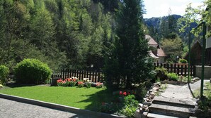 Un jardin avec une clôture en bois, un chemin de pierres et une maison avec un toit rouge.