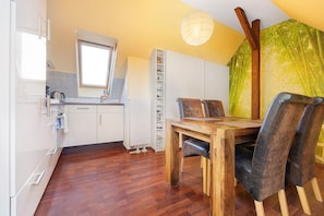 Une cuisine moderne avec des meubles blancs, une table à manger en bois et une fenêtre.