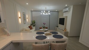 A modern dining area with a white table, four chairs, and a central island with a plant and decorative items.