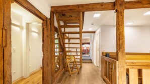 Interior em madeira com escada, uma cadeira de madeira e uma mesa.