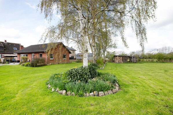 A residential area with a well-maintained lawn, a large tree, and a stone wall.