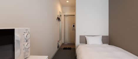 Een hotelkamer met een bed, een magnetron en een kleine keukenhoek.