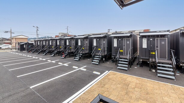 A row of portable restrooms with external stairs, a parking lot, and a clear sky. - HOTEL R9 The Yard Karatsu (Karatsu)