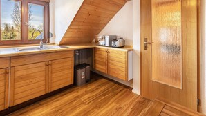 A kitchen with wooden cabinets, a sink, a trash bin, and a microwave. - Apartment 'Anne' with Lake View, Balcony and Wi-Fi (Öhningen)