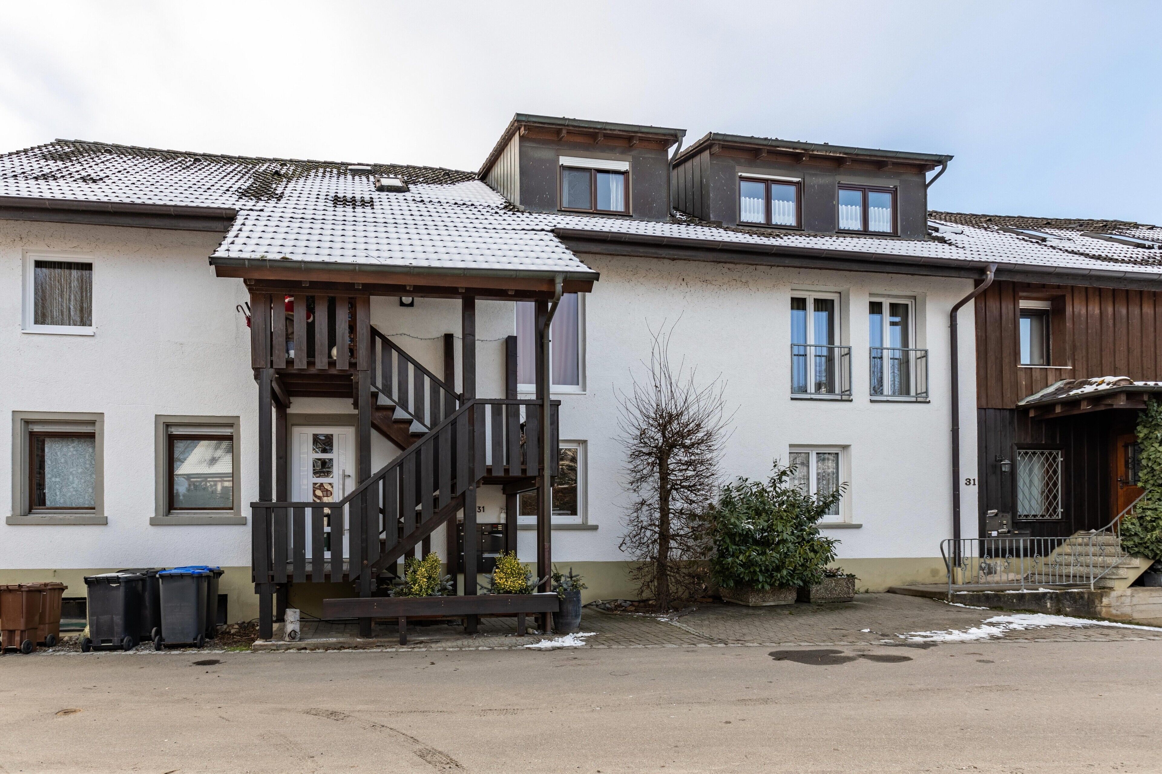 Eine Reihe von Wohnhäusern mit einer zentralen Treppe, Fenstern und einer kleinen Grünfläche.