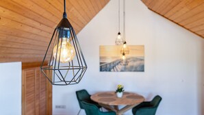 A dining area with a wooden ceiling, a round table with chairs, and pendant lighting. - Apartment 'Anne' with Lake View, Balcony and Wi-Fi (Öhningen)