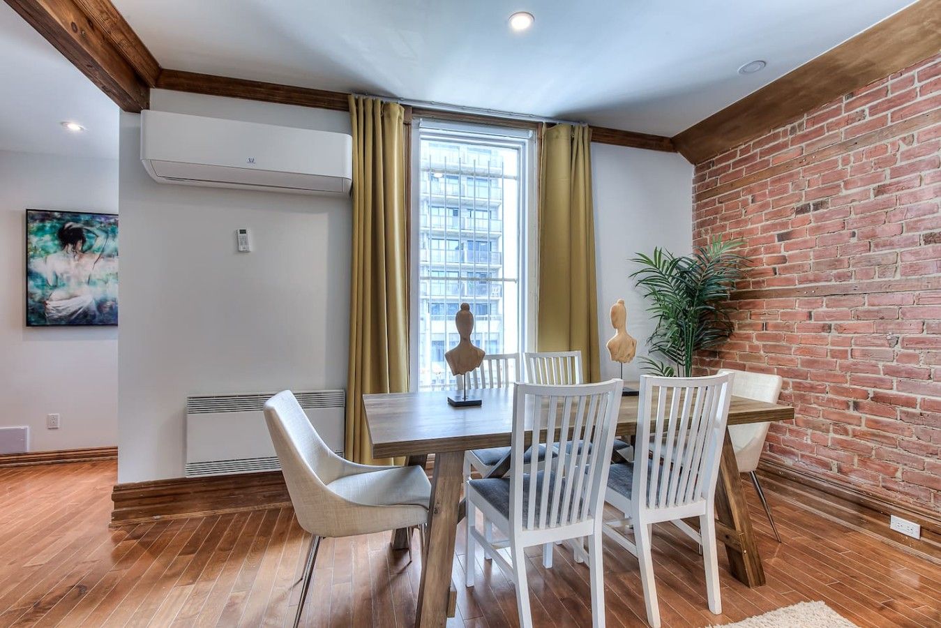A dining area with a brick wall, a window with curtains, and a table with chairs.