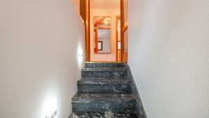 A staircase with a wooden handrail leading to a room with a door and a light fixture. - Apartment 'Haus Johanna' with Mountain View, Balcony and Wi-Fi (Todtmoos)