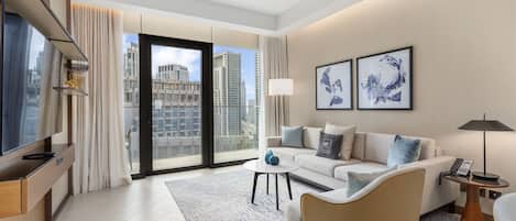 A modern hotel room with a large window, a sofa, a coffee table, and a TV.