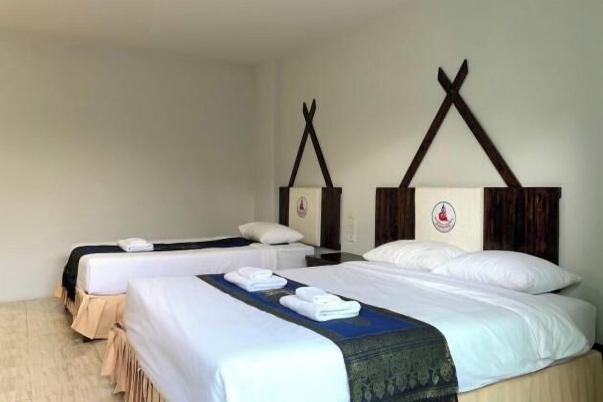 A hotel room with two beds, a wooden headboard, and a wall-mounted clock.