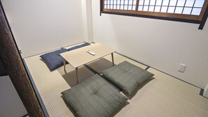 Une pièce avec un sol recouvert de tatamis, une petite table basse et des coussins.
