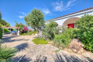 A house with a stone pathway, a red door, and lush greenery.