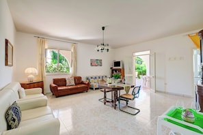 A living room with a sofa, a dining table, and a TV.
