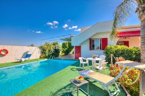 A swimming pool with a sunshade, lounge chairs, and a table with a fruit bowl. - Villa Strea with pool (Nardò)