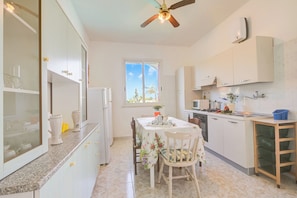 A kitchen with a dining table, chairs, cabinets, a ceiling fan, and a window. - Villa Strea with pool (Nardò)