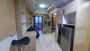 Eine kompakte Küche mit Kühlschrank, ein Essbereich mit einer Bank und Blick auf die Stadt durch ein großes Fenster.