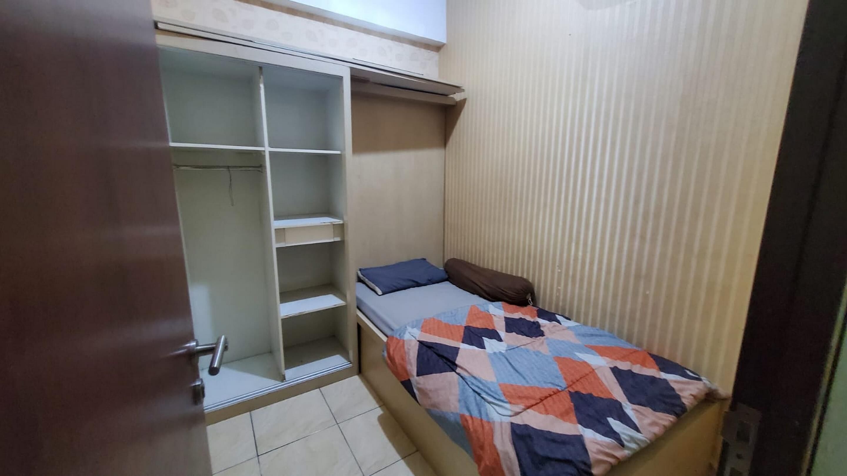 A small bedroom with a bed, a wardrobe, and a door.