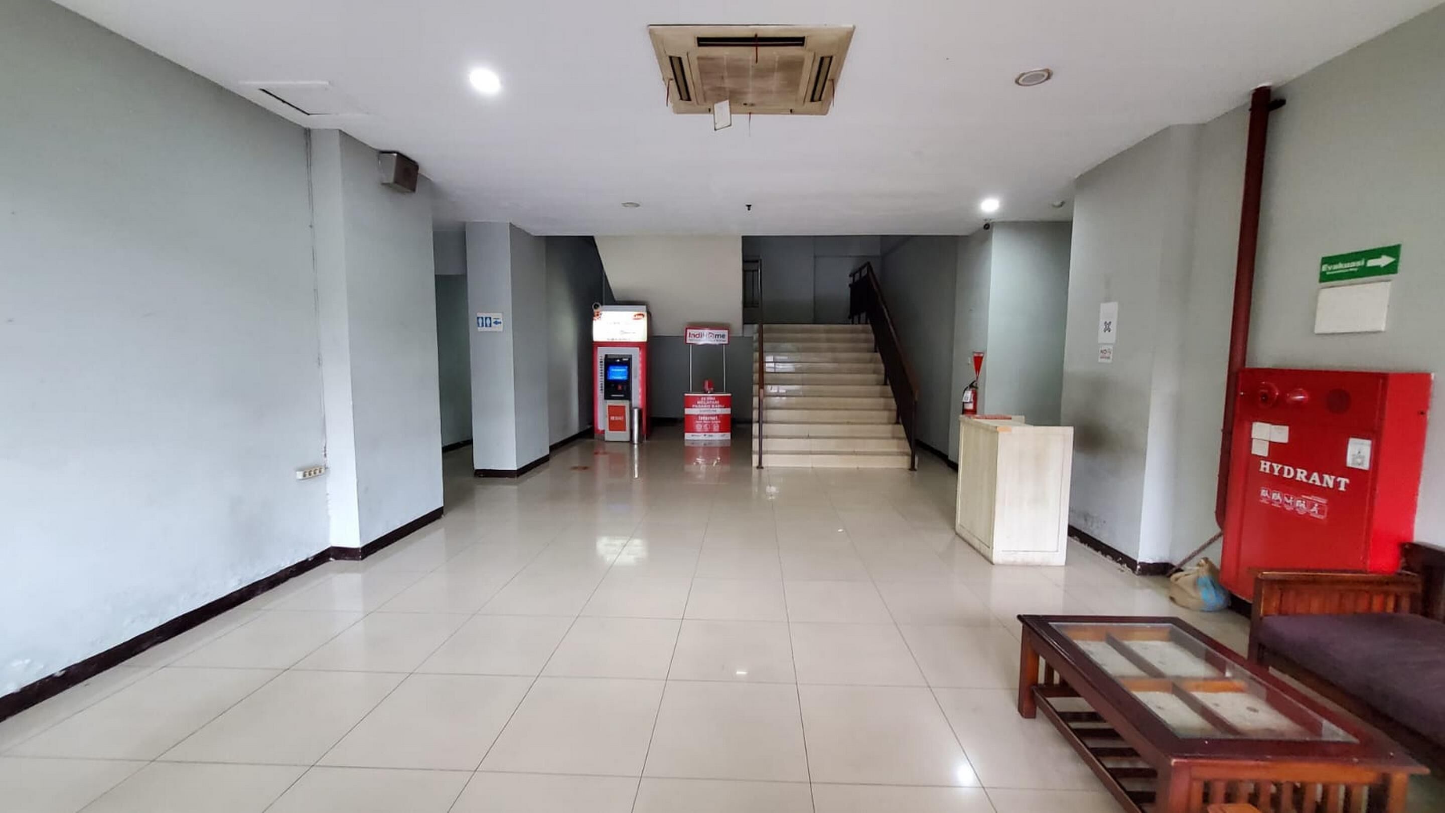 A clean, well-lit hallway with a reception desk, a staircase, and a fire extinguisher.