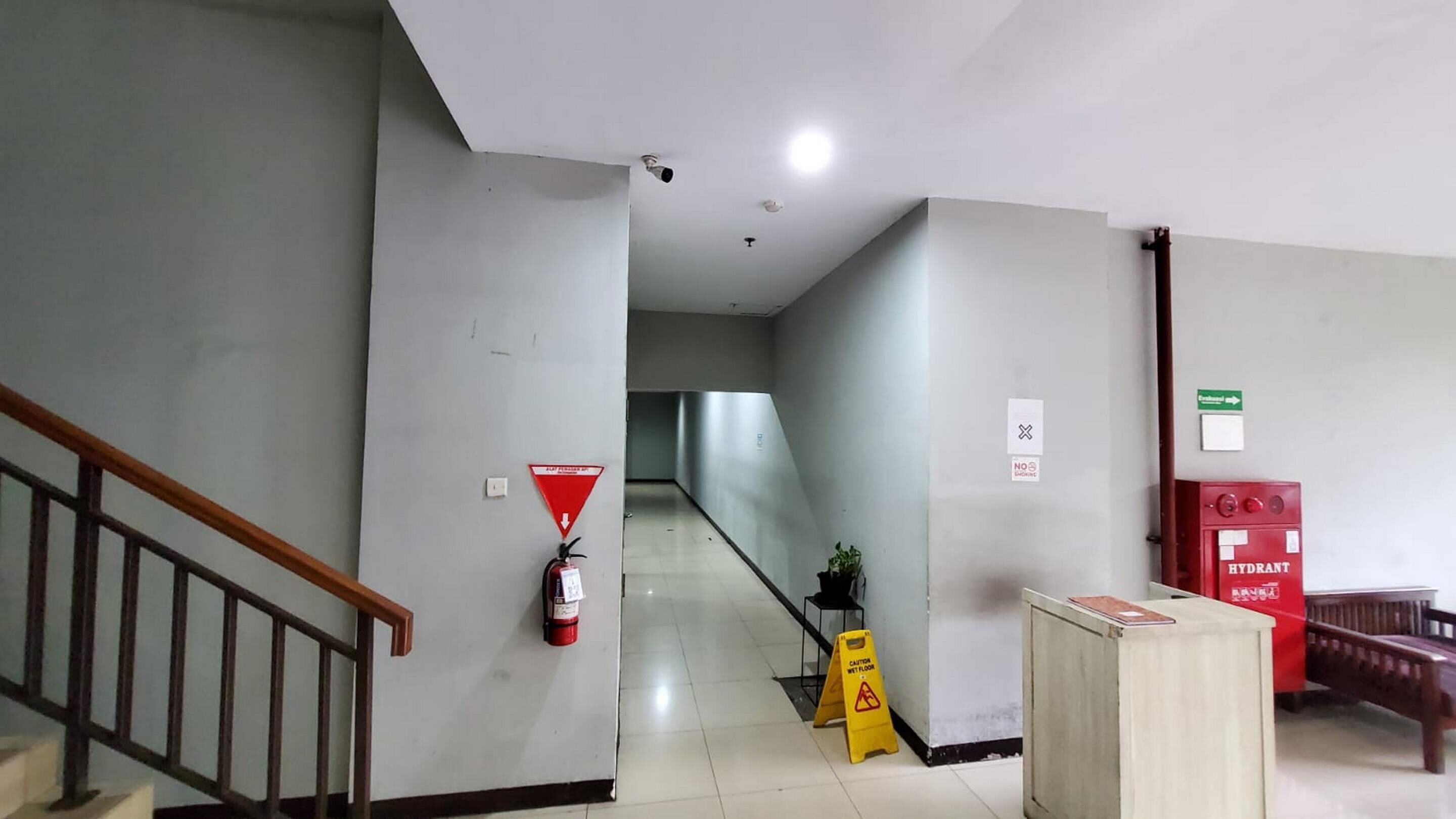 A hallway with a fire extinguisher, a caution sign, and a hydrant.