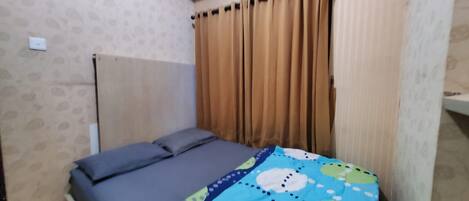 A small room with a bed, a window with curtains, and a patterned wall.