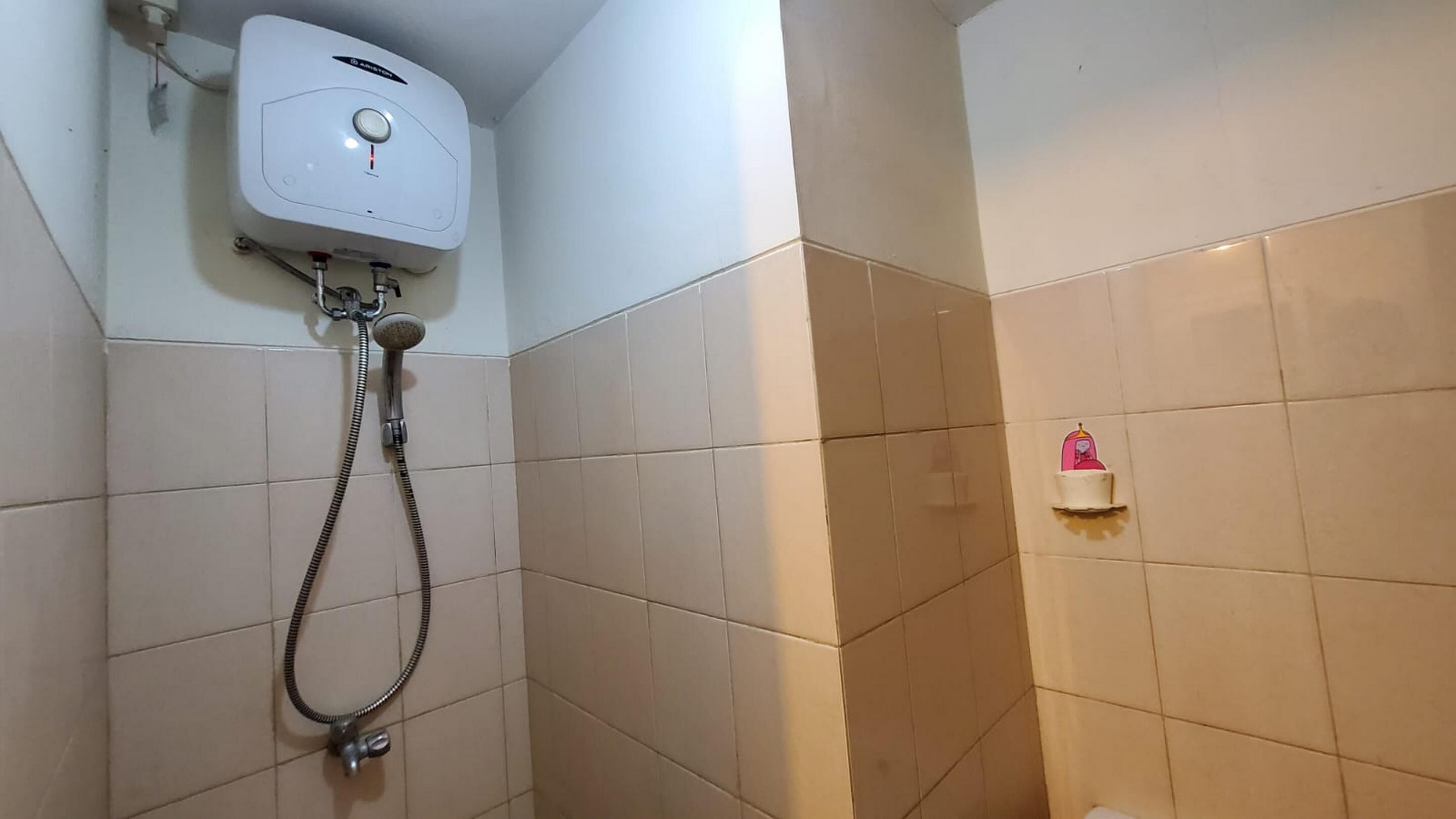 Un baño con ducha, inodoro y un estante pequeño con un objeto rosa.