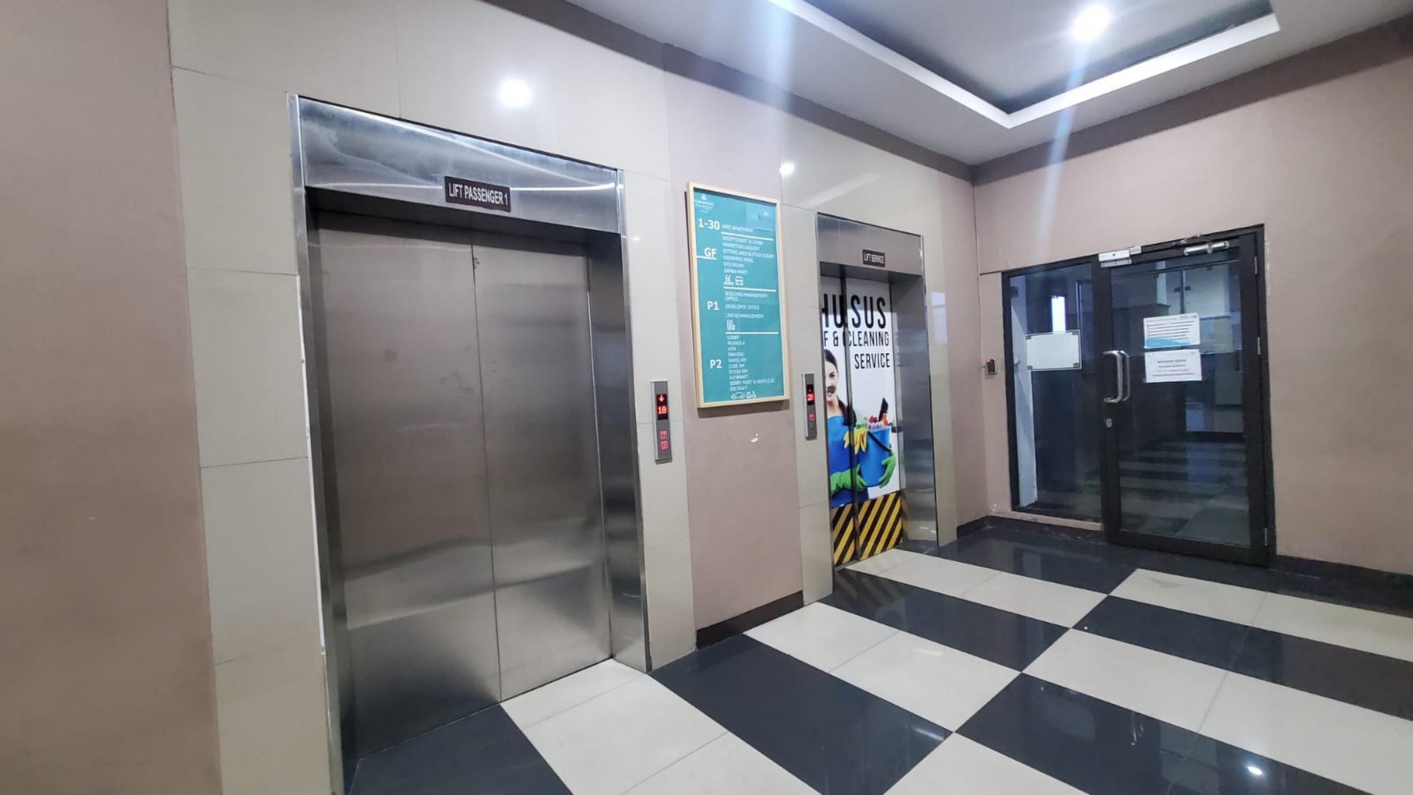 An elevator with a sign indicating it is for passenger use, a cleaning service poster, and a checkered floor pattern.