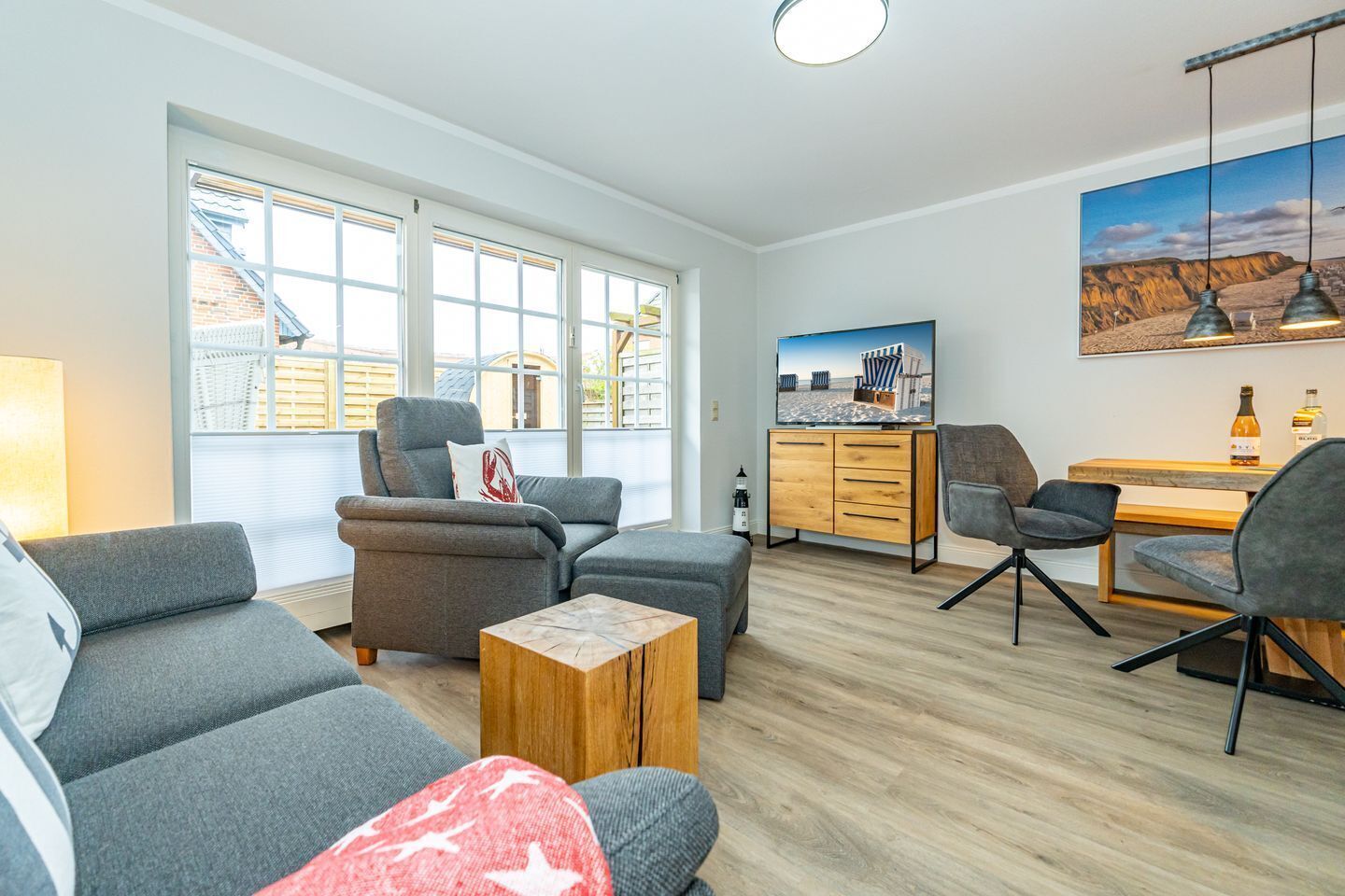 A modern living room with grey sofas, a wooden coffee table, and a TV on a wooden cabinet.
