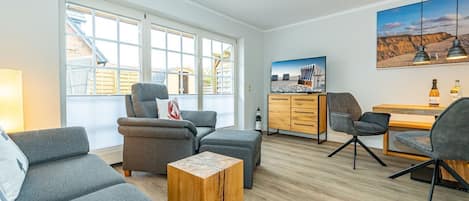 En moderne stue med grå sofaer, et træbord og et fjernsyn på et træskab.
