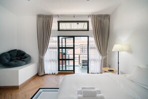 Een hotelkamer met een bed, een zithoek, een lamp en uitzicht door een glazen deur.