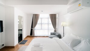 Een hotelkamer met een bed, een stoel, een bureau en een raam met gordijnen.